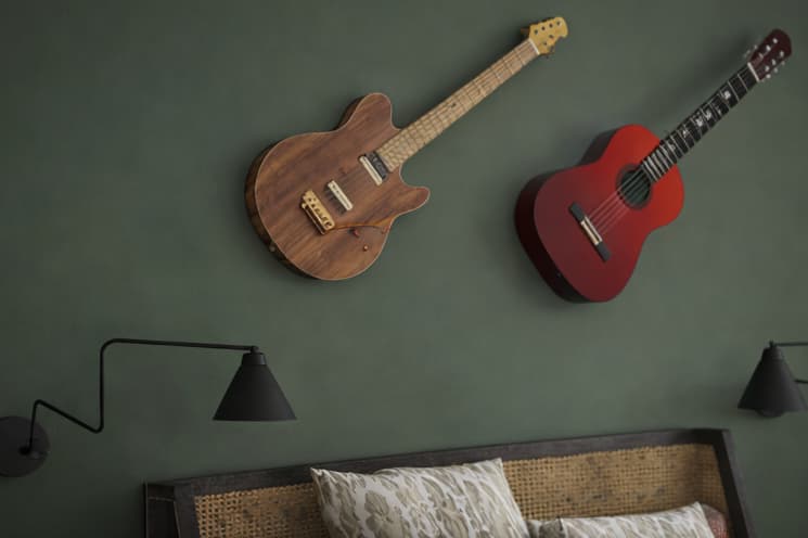 Detailaufnahme einer grünen Akzentwand im Schlafzimmer mit zwei dekorativ aufgehängten Gitarren und schwarzer Wandlampe.